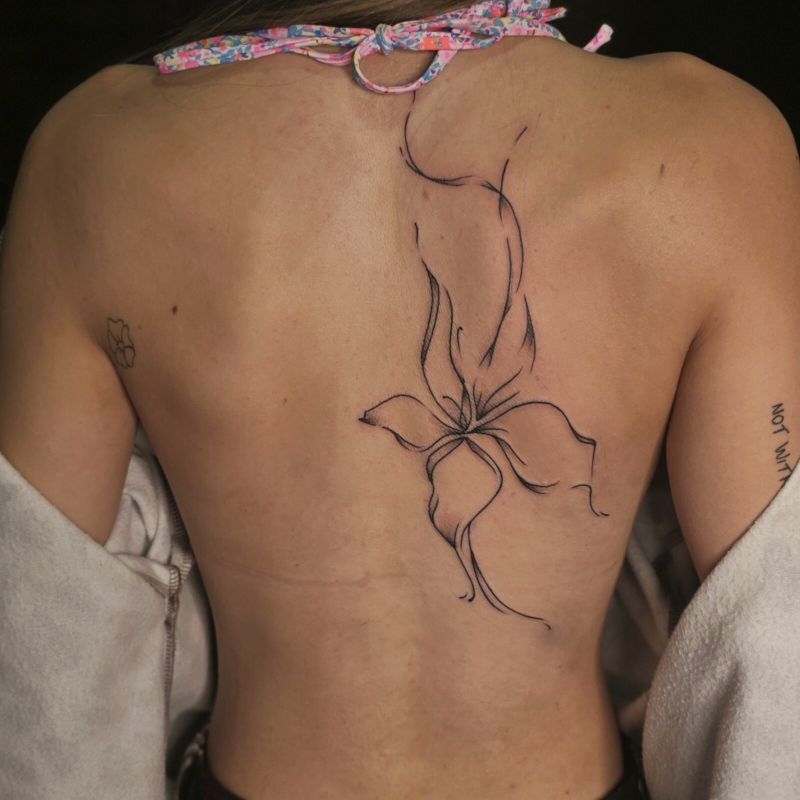 Fine line sketch-style flower running down the centre of a woman's back