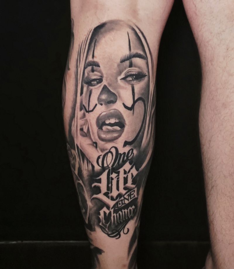 Chicano style black and grey calf piece: a woman's portrait with clown face paint above "One Life One Chance" script lettering