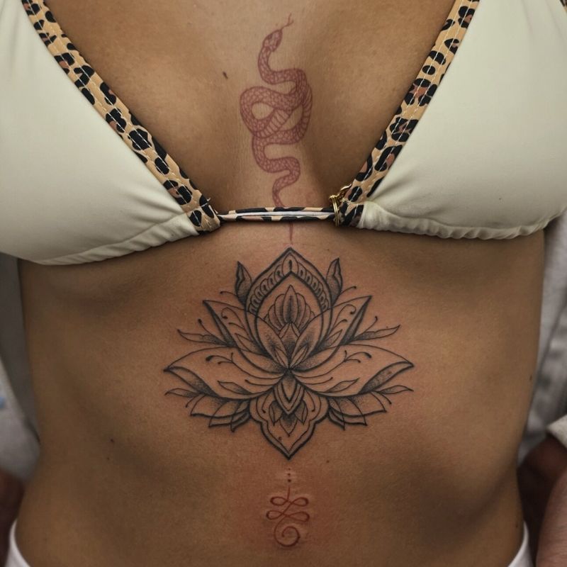 Ornamental lotus mandala on the sternum with a fine line snake above it